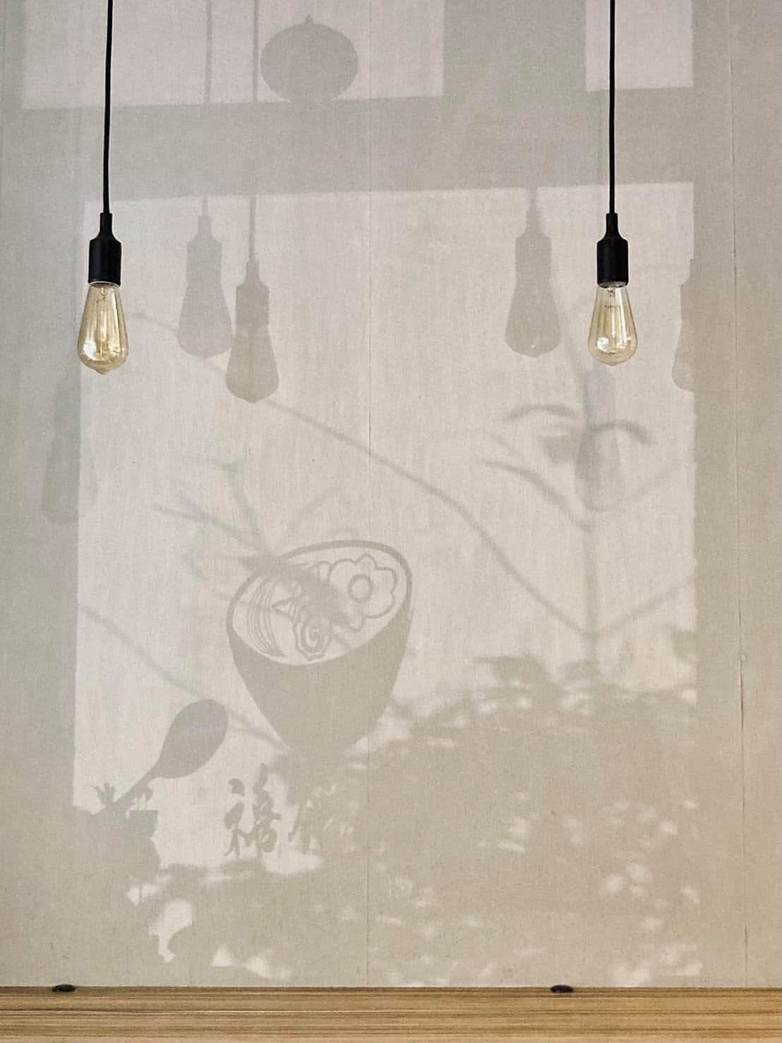 禧鍋燒 Logo 在店內牽網牆面的光影投射